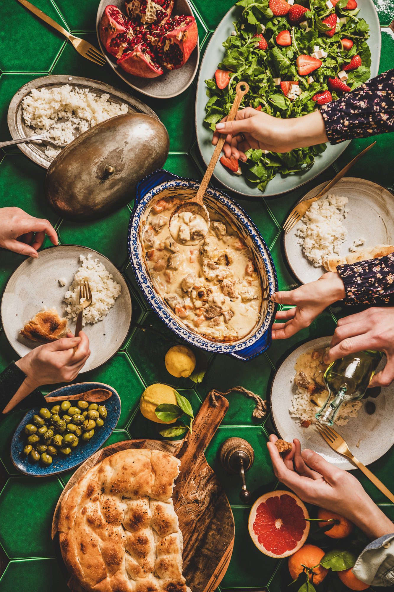 Yeşil çini masa üzerinde Türk yemeklerini elleriyle yiyen insanlar