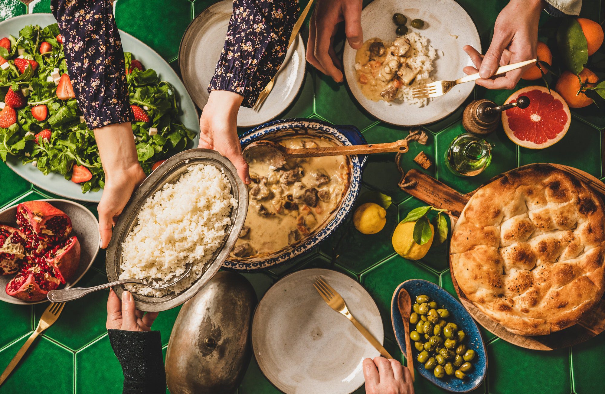 People passing Turkish foods over celebration dinner table, top view